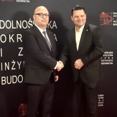 Okręgowy Inspektor Pracy we Wrocławiu Andrzej Pogórski z gościem wydarzenia na tle ścianki